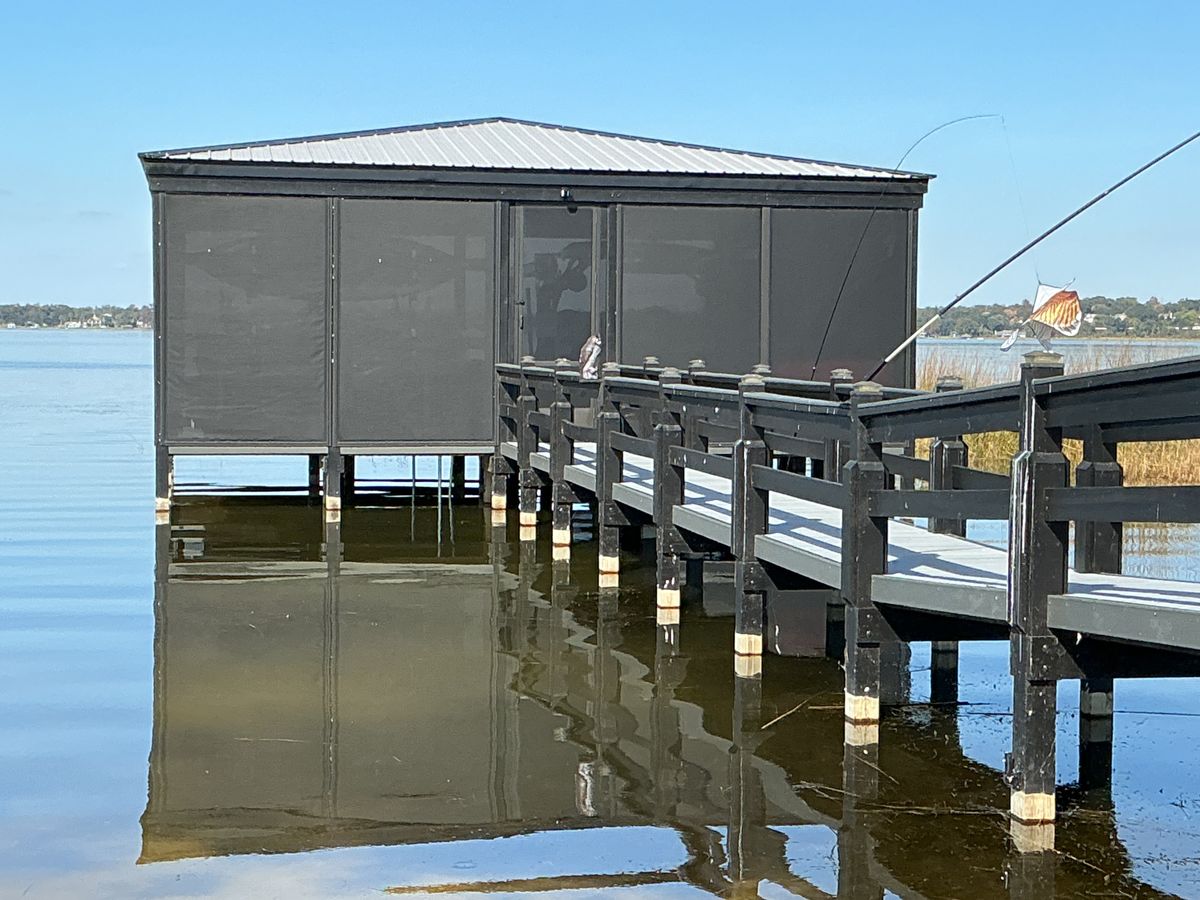 A dock house on the lake enclosed in dark motorized screens