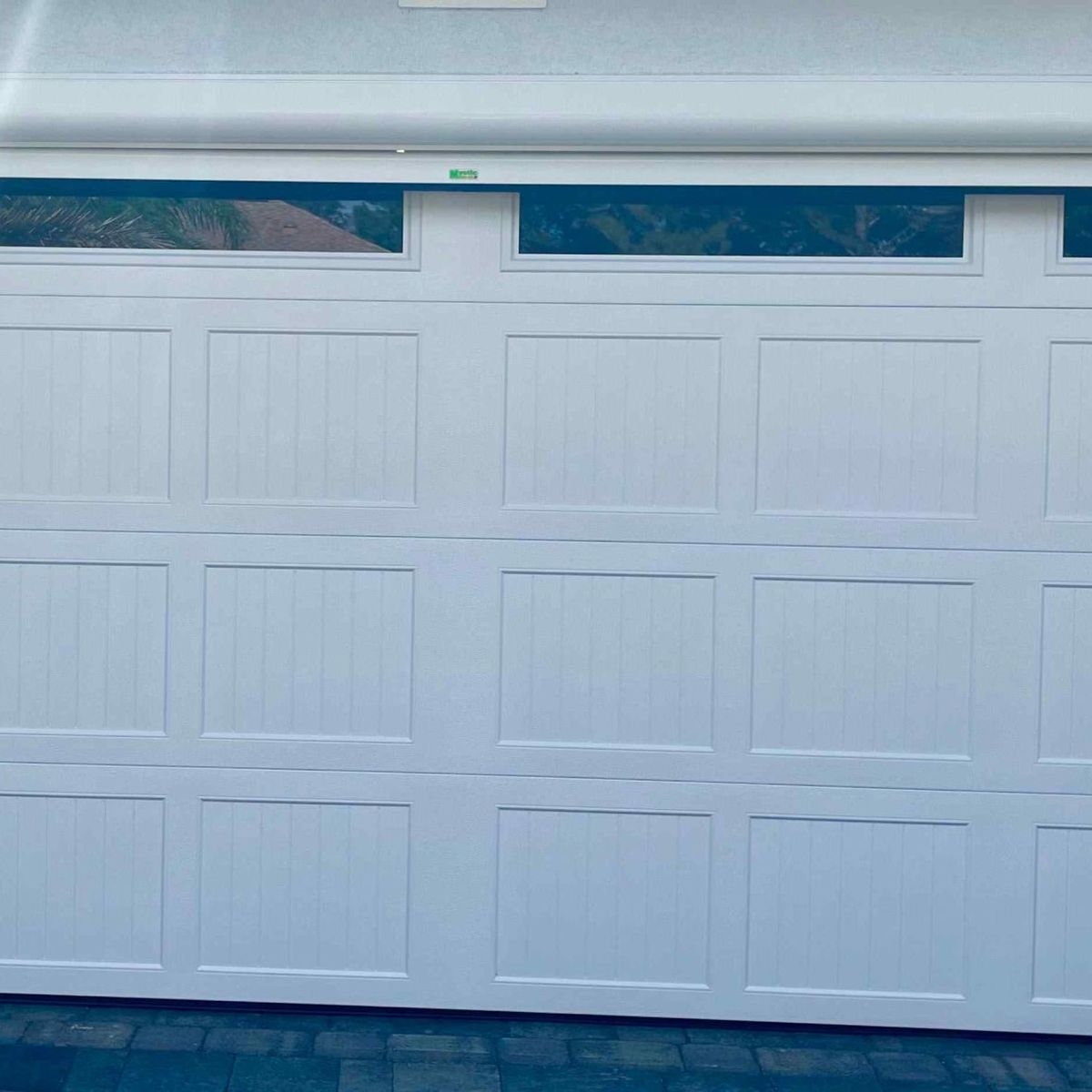 A new white sectional garage door on a stucco home